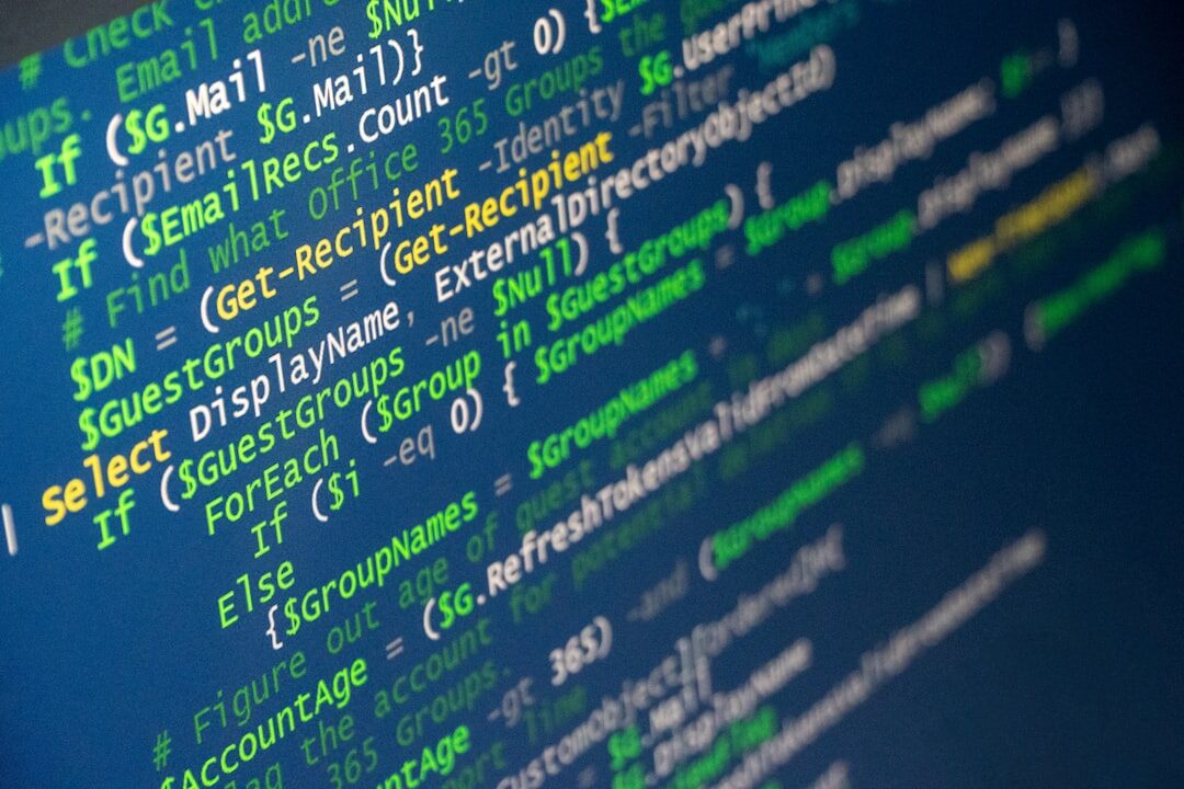 Software code displayed on multiple dark monitors in a developer workspace